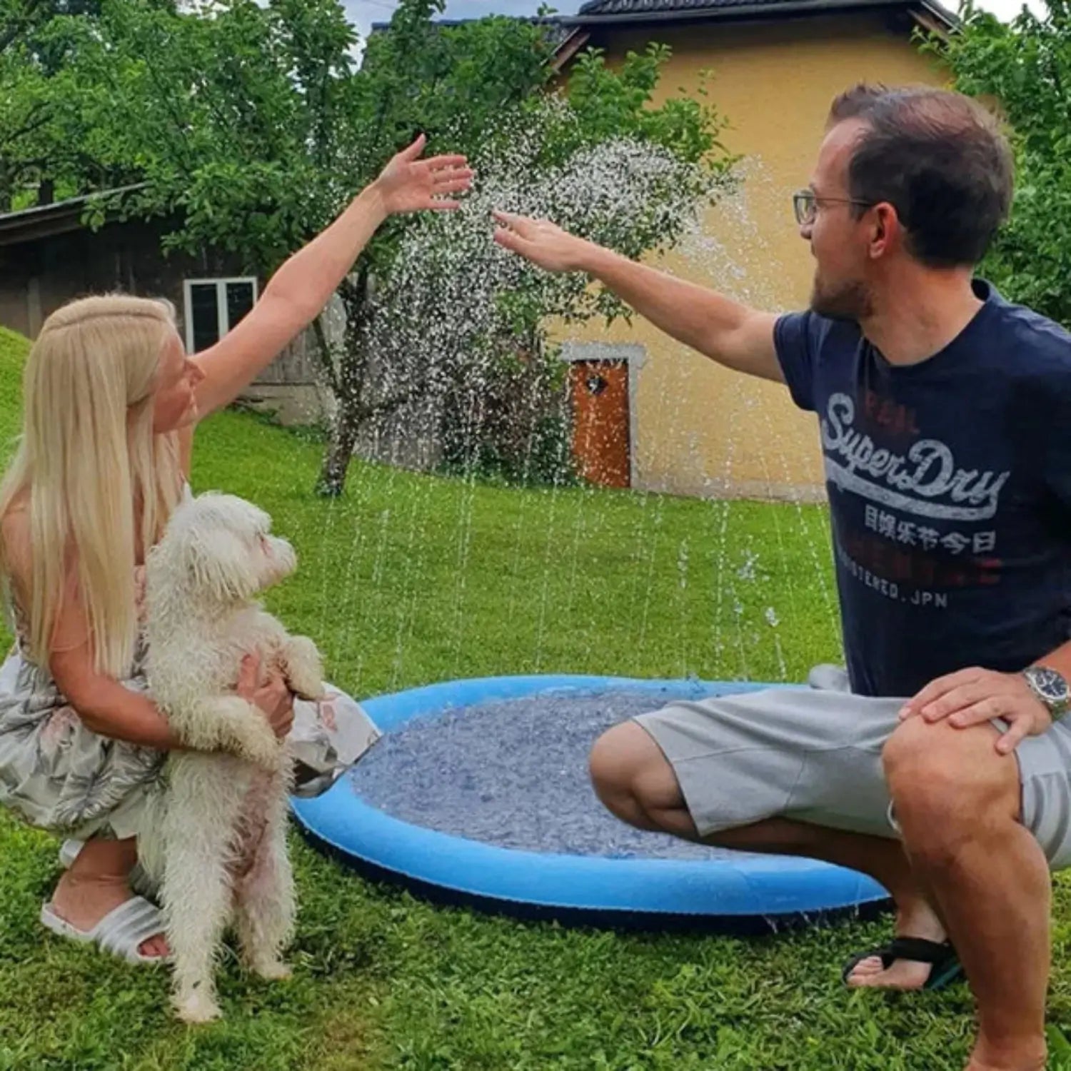 Hondeneigenaar met hondje spelen met water spray mat
